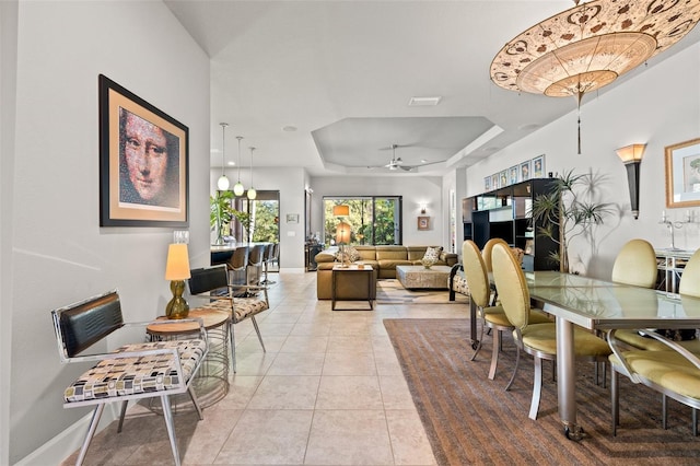 dining space featuring light tile patterned floors, visible vents, a raised ceiling, and baseboards