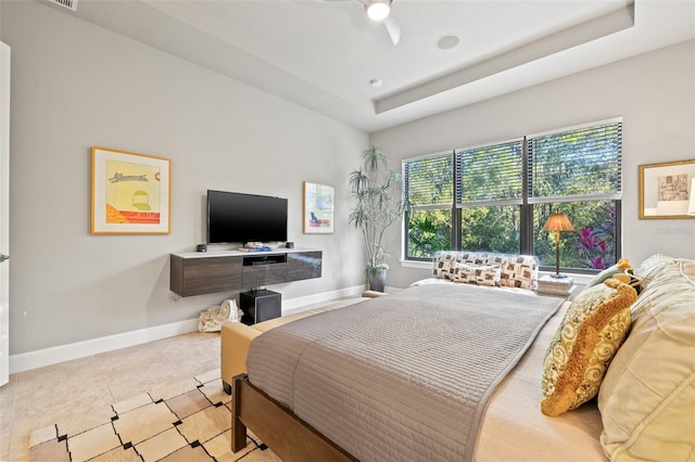 bedroom featuring tile patterned floors, baseboards, and a raised ceiling