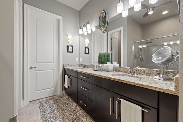 bathroom with double vanity, a ceiling fan, a stall shower, and a sink