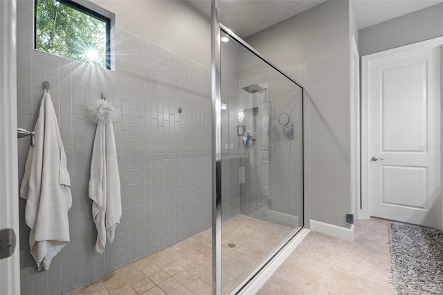 full bath featuring tile patterned flooring, a shower stall, and baseboards