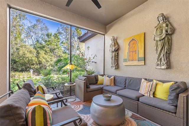 living area featuring a ceiling fan and a textured wall