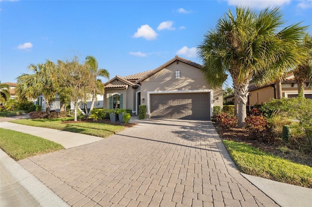 9708 Highland Park Pl, Palmetto, FL 34221 - mediterranean / spanish-style home featuring an attached garage, decorative driveway, stucco siding, a tile roof, and a front yard