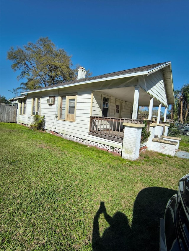 rear view of house with a yard, a chimney, and fence