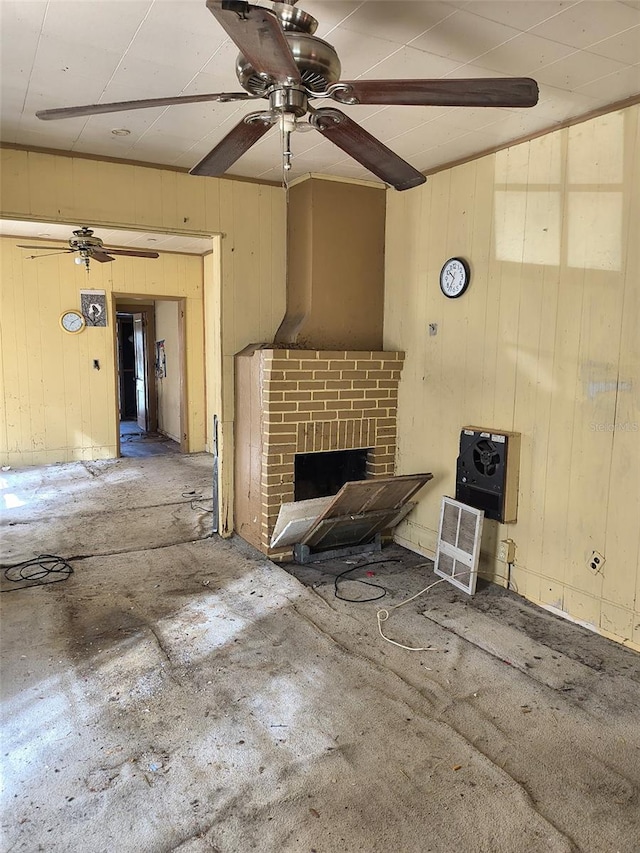 unfurnished living room featuring ceiling fan and a brick fireplace