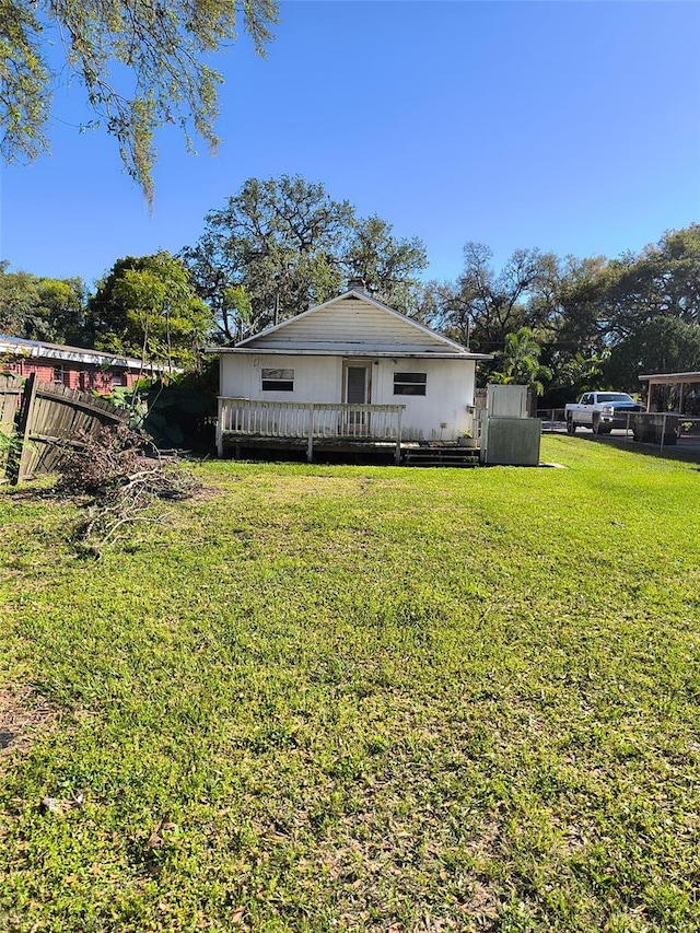 view of front facade with a front yard, fence, and a wooden deck