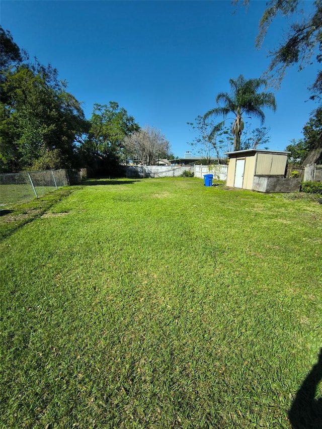 view of yard featuring a storage unit, fence, and an outdoor structure