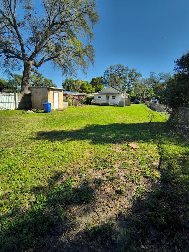 view of yard featuring a storage shed, fence, and an outdoor structure