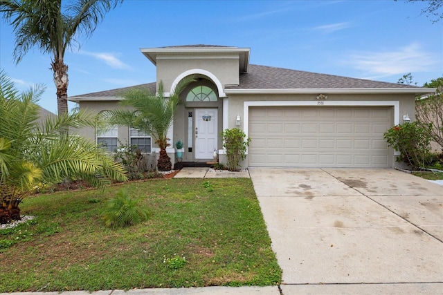 view of front of home with a garage, driveway, a front yard, and stucco siding