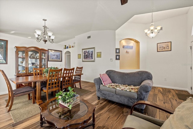 living area with arched walkways, visible vents, an inviting chandelier, wood finished floors, and baseboards