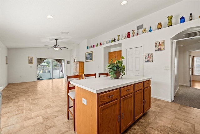 kitchen with visible vents, a kitchen island, a kitchen breakfast bar, vaulted ceiling, and light countertops