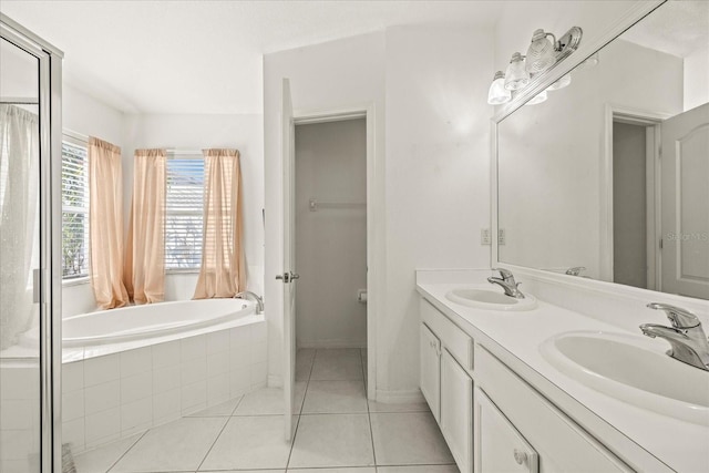 bathroom with double vanity, a garden tub, a sink, and tile patterned floors