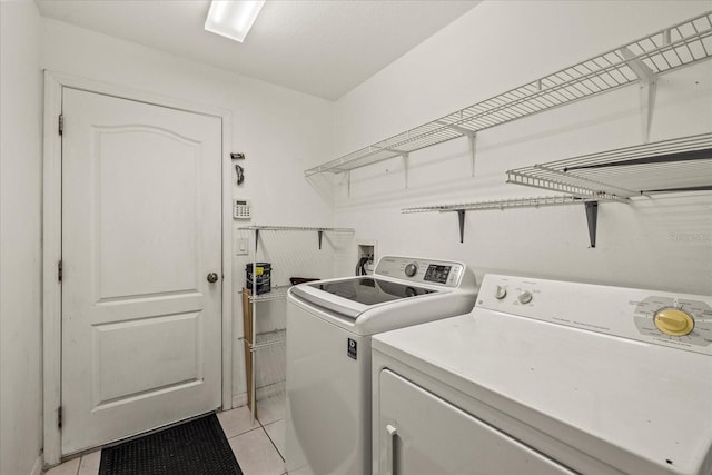 laundry room featuring laundry area, washer and dryer, and light tile patterned flooring