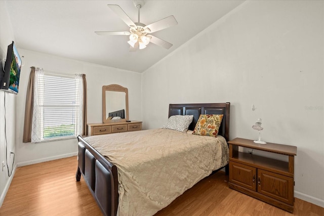 bedroom with light wood finished floors, baseboards, vaulted ceiling, and a ceiling fan