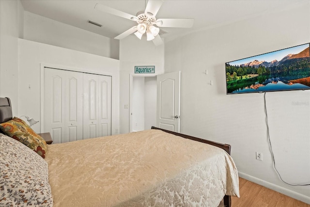 bedroom featuring baseboards, visible vents, ceiling fan, wood finished floors, and a closet