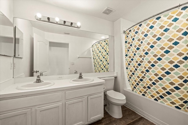 bathroom with toilet, double vanity, a sink, and visible vents