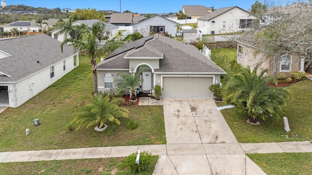 view of front of property with a garage, a shingled roof, concrete driveway, a residential view, and a front yard