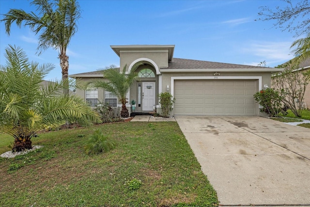 view of front of property with a garage, driveway, a front lawn, and stucco siding