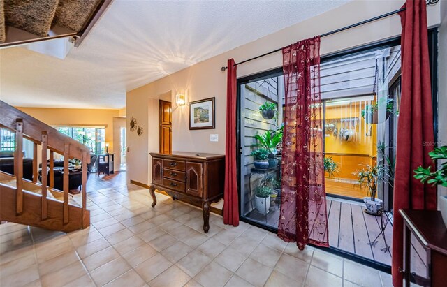 foyer entrance with a textured ceiling and light tile patterned floors