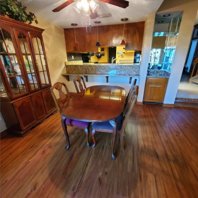 dining room featuring a textured ceiling, a ceiling fan, and dark wood-type flooring