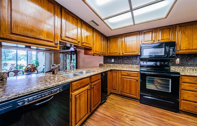 kitchen with black appliances, brown cabinetry, decorative backsplash, and light wood-style floors