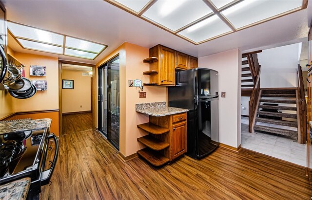 kitchen with brown cabinetry, black appliances, and open shelves