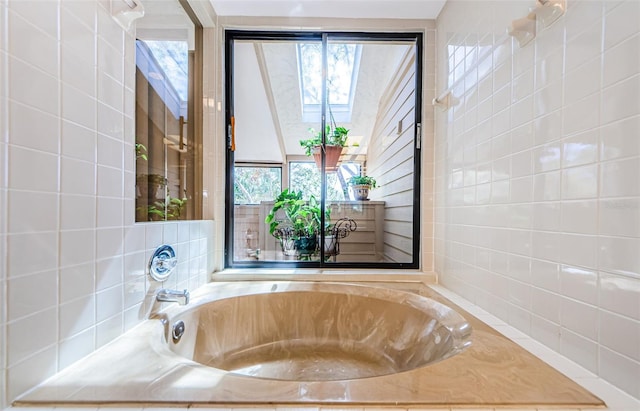 bathroom with a bath, a skylight, and tile walls