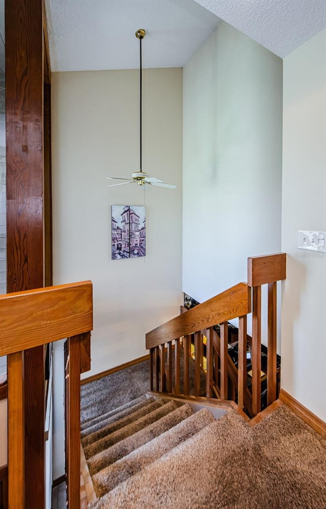 staircase featuring carpet floors, a textured ceiling, and baseboards