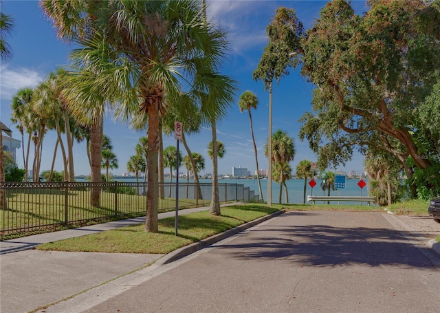 view of road with curbs, traffic signs, sidewalks, and a water view