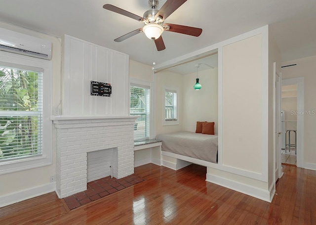 unfurnished bedroom featuring wood-type flooring, baseboards, and a wall mounted AC