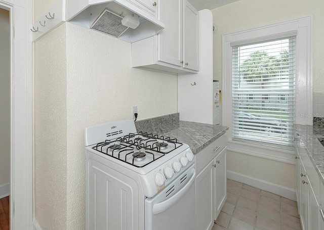 kitchen with under cabinet range hood, white gas range, baseboards, and white cabinets