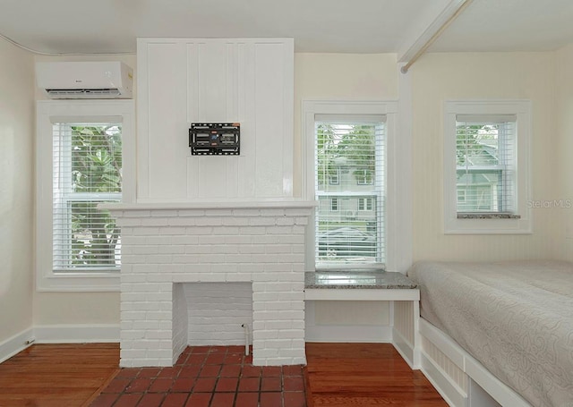 bedroom with dark wood-style floors, an AC wall unit, multiple windows, and baseboards