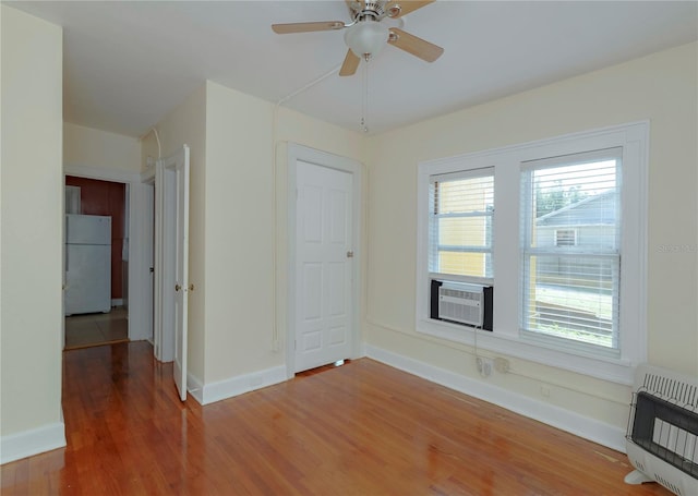 unfurnished room with cooling unit, plenty of natural light, heating unit, and wood finished floors