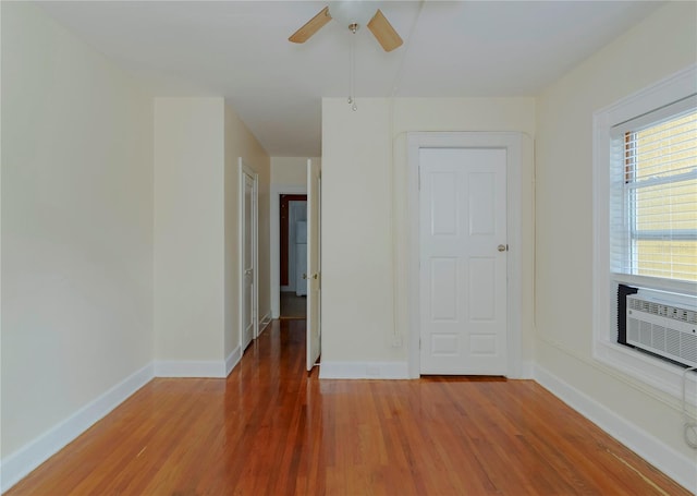 empty room with a ceiling fan, cooling unit, light wood-style flooring, and baseboards