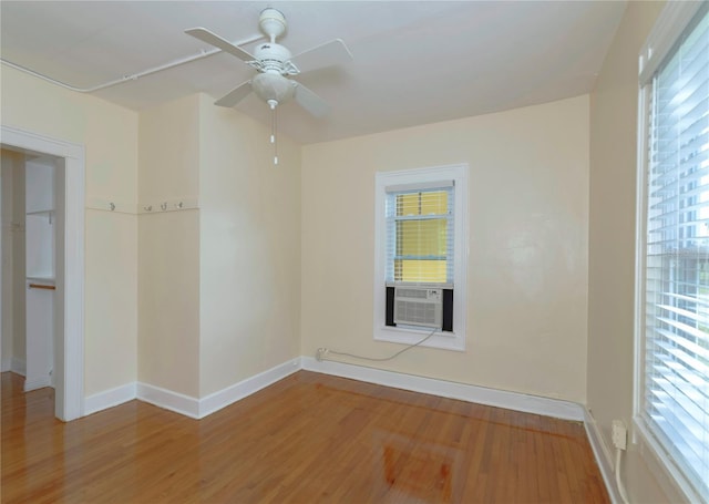 empty room with wood finished floors, cooling unit, and a wealth of natural light