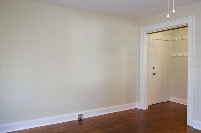 unfurnished room with dark wood-style flooring and baseboards