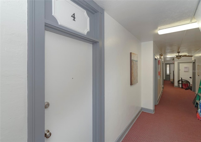 hallway featuring carpet floors and baseboards