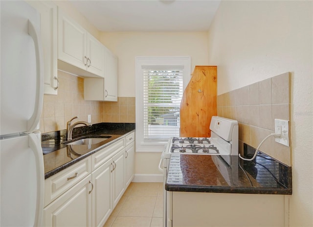 kitchen featuring light tile patterned floors, tasteful backsplash, a sink, dark stone countertops, and white appliances