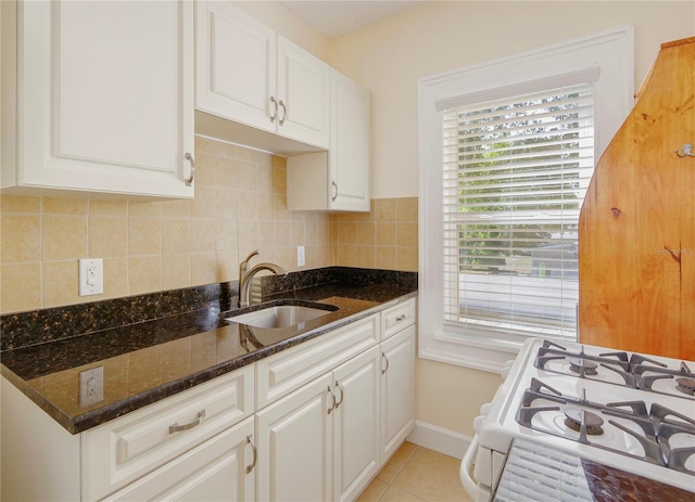 kitchen with light tile patterned flooring, backsplash, a sink, and white gas stove