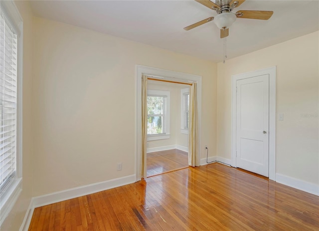 spare room with light wood-style floors, ceiling fan, and baseboards