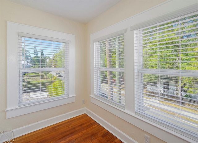 unfurnished room with dark wood-type flooring, a healthy amount of sunlight, and baseboards