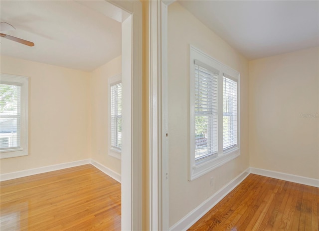 spare room with a ceiling fan, light wood-style flooring, and baseboards