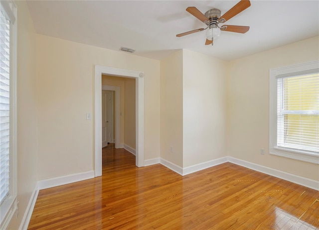 unfurnished room featuring ceiling fan, light wood-type flooring, visible vents, and baseboards