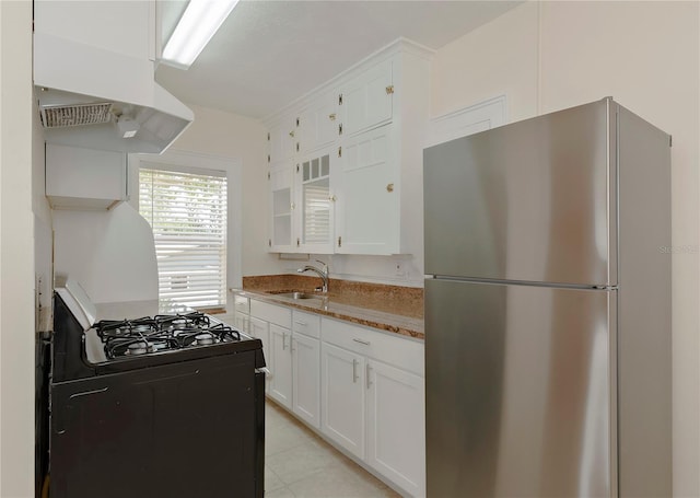 kitchen with black range with gas cooktop, freestanding refrigerator, under cabinet range hood, white cabinetry, and a sink