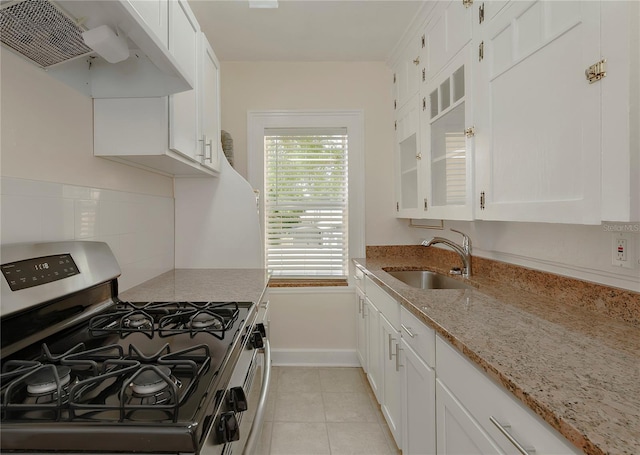 kitchen with stainless steel gas range, a sink, white cabinets, and under cabinet range hood