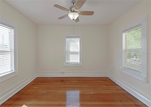 empty room with ceiling fan, light wood-type flooring, and baseboards
