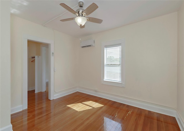 unfurnished room with ceiling fan, baseboards, wood finished floors, and a wall mounted AC