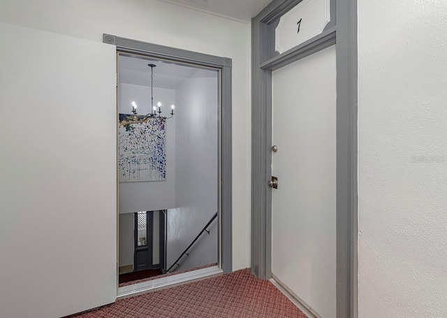 hallway featuring dark carpet and a notable chandelier