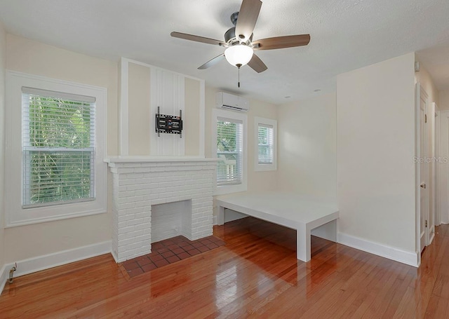mudroom with light wood-style floors, a brick fireplace, and a wall unit AC