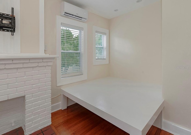 interior space with a wall unit AC, baseboards, and wood finished floors