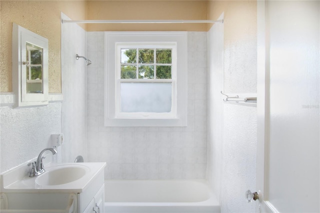 full bath featuring a textured wall, bathing tub / shower combination, and vanity